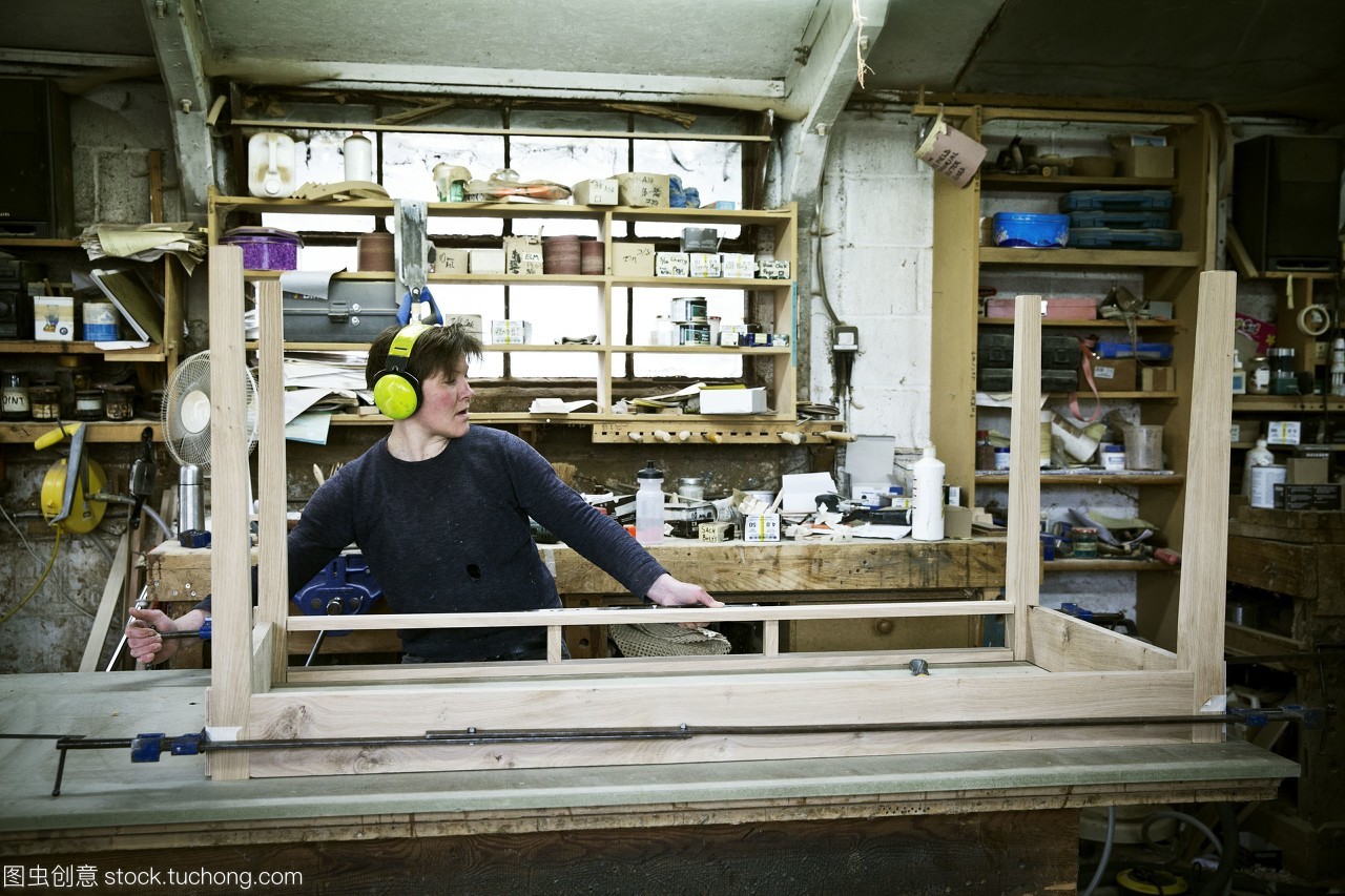 一个女人在家具制造商的车间工作组装一个表。